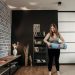 Plus size woman rolling a yoga mat in a stylish indoor setting with modern decor.